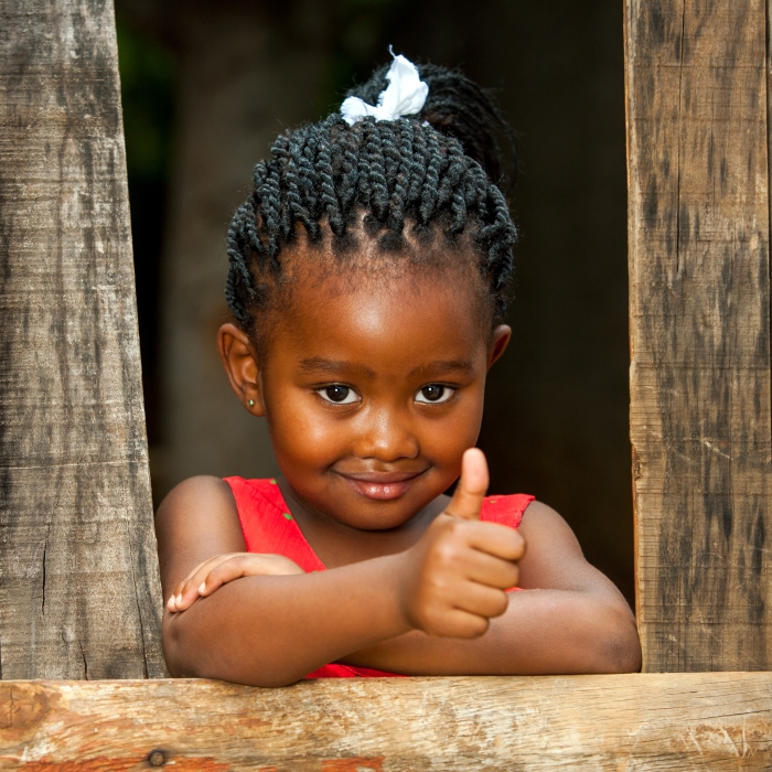 Little African Girl At Wooden Fence With Thumbs Up.